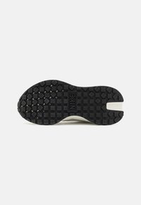 Semelle en caoutchouc noir de sneaker avec une surface texturée, arborant un logo Nike bien en vue et une forme ondulée. Accents gris subtils visibles.