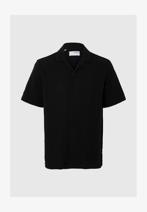 Melnas īsām piedurknēm krekls, izgatavots no teksturētas auduma, ar izgriezumu apkakli un sešām priekšējām pogām, ar brīvu piegriezumu un taisnu apakšmalu.