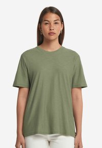 Olivgrön t-shirt i mjukt tyg. Avslappnad passform med korta ärmar och rund halsringning. Har en slät, strukturerad yta.