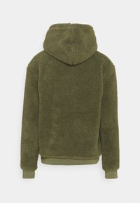 Olivenfarget hettejakke laget av myk, teksturert fleece. Har en standard passform med ribbede mansjetter og hem, ingen synlige logoer eller utsmykninger.