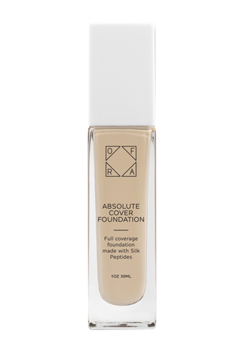 Genomskinlig glasflaska med ett vitt fyrkantigt lock, fylld med en ljus beige flytande foundation, märkt "Absolute Cover Foundation."
