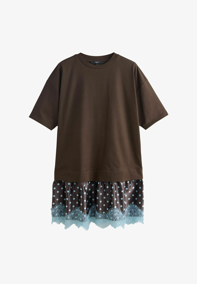 Haut oversize à manches courtes de couleur marron foncé superposé à une jupe marron à pois avec un bord en dentelle bleue le long de l'ourlet.