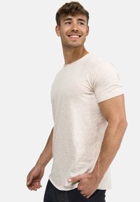 Licht beige t-shirt met korte mouwen, gemaakt van een zachte, gestructureerde stof. Het ontwerp heeft een ronde halslijn en een ontspannen pasvorm.