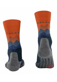 Calcetines coloridos con un puño naranja, patrón de montañas en gris, azul y púrpura, talón reforzado y planta de pie texturizada en gris. Presenta el nombre de la marca "FALKE."