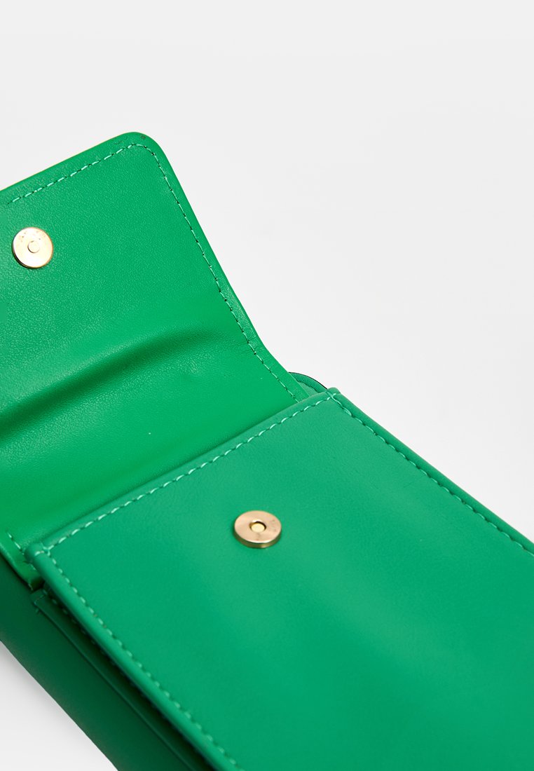 Interior de una cartera de piel verde con una textura suave, que cuenta con botones a presión dorados y costuras en contraste a lo largo de los bordes.