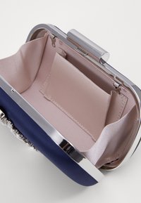 Borsa a mano blu navy con una cornice in metallo argentato, interno foderato in tessuto rosa chiaro, dotata di una piccola tasca e di una texture liscia.