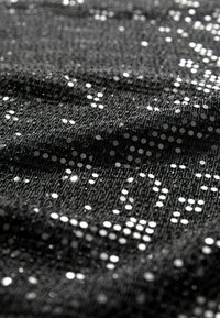 Černá texturovaná látka s rozházenými stříbrnými flitry, vytvářející třpytivý efekt po povrchu, s jemným splývavým materiálem.