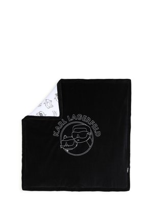 Couverture noire avec dessin en ligne blanche d'une personne et d'un chat portant des lunettes de soleil et le texte "KARL LAGERFELD,", coin replié pour montrer le dessous blanc avec des motifs de croquis similaires.
