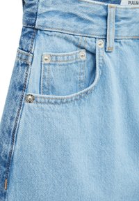 Shorts en denim bleu clair avec coutures visibles, poche latérale et boutons métalliques. Texture douce et coupe classique.