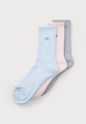 Trois paires de chaussettes dans des couleurs pastel : bleu clair, rose clair et gris clair. Elles présentent une texture côtelée et un petit logo sur chacune.