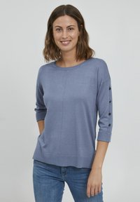 Hellblauer Strickpullover mit Dreiviertelärmeln, der schwarze Knopfakzente entlang des Ärmels sowie einen gerippten Ausschnitt und Saum aufweist.