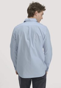 Lichtblauwe hemd met lange mouwen en een knoopkraag, voorzien van een yoke-design, rugplooi en verstelbare manchetten. Glad textuur van de stof.