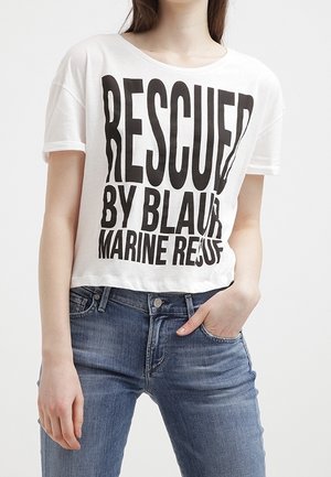 Biała krótka koszulka z dużym czarnym napisem "URATOWANY PRZEZ BLAUR MARINE RESCUE" w zestawieniu z niebieskimi dżinsami.