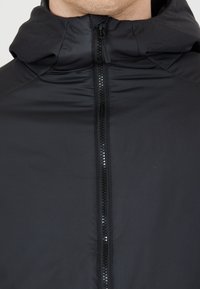 Sort letvægts zip-jakke med høj krave og hætte. Den har en glat tekstur og en central lynlås med en blank finish.