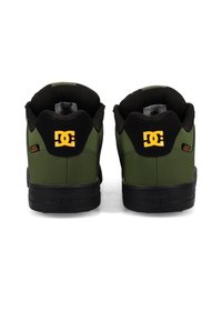 Zelené vysoké tenisky so čiernymi akcentmi, s textúrovaným zvrškom, gumovou podrážkou a výrazným žltým logom na päte.