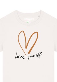 Witte katoenen t-shirt met een bruine hartafbeelding en de tekst "hou van jezelf" in zwarte schrijfletters eronder.