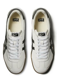 Sneaker bianche in pelle con accenti neri, caratterizzate da un classico design con lacci, strisce laterali testurizzate e suola in gomma.