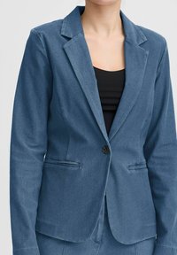 Jeansblazer i blått, skräddarsydd passform med knappstängning, slagkragar och sidofickor. Slät textur med lätt glans.