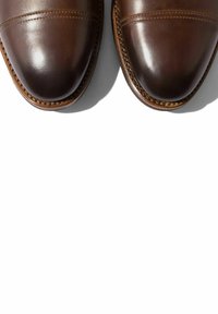 Scarpe da uomo in pelle marrone con finitura lucida, dotate di punta arrotondata, cuciture sottili e suola cucita.