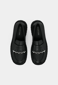 Black loafers with a textured leather upper, featuring a decorative silver accent and a chunky rubber sole for added grip and durability.