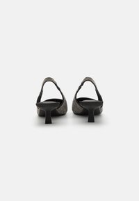 Talons aiguille noirs à bride arrière, en matériau tissé texturé, avec un petit talon bloque et des accents décoratifs à l'arrière. Design épuré, style minimaliste.