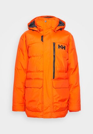 Chaqueta aislante de color naranja brillante con cierre de cremallera, detalles en negro, dos bolsillos frontales y capucha con cordón. Presenta un logo en el pecho y un bolsillo con cremallera.