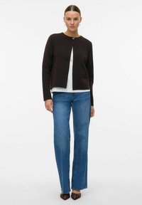 Brauner Cardigan mit rundem Ausschnitt, leichtem Material, einem Knopfverschluss, kombiniert mit hellblauen geraden Jeans und braunen Schuhen.