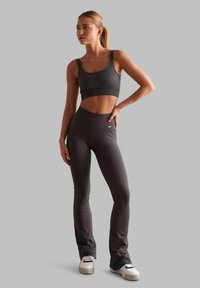 Top sportivo grigio a coste e leggings svasati abbinati, realizzati in tessuto testurizzato. L'outfit presenta una vita alta e un dettaglio di branding discreto.