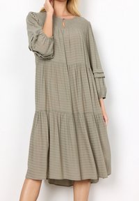 Langsleeve, gelaagde jurk in gedempt olijfgroen, met een textuur van horizontale strepen, een keyhole-hals en geraffineerde mouwen.