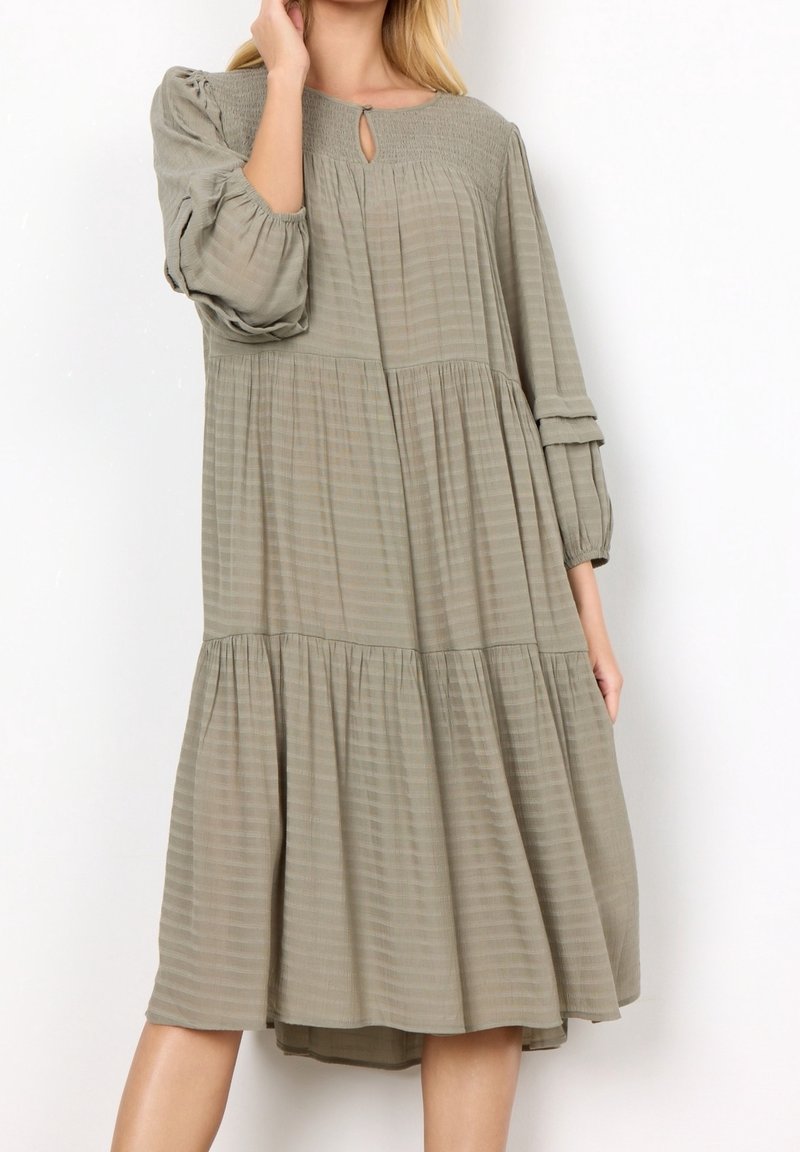 Abito a maniche lunghe a strati in verde oliva smorzato, con strisce orizzontali testurizzate, scollatura a chiave e maniche arricciate.