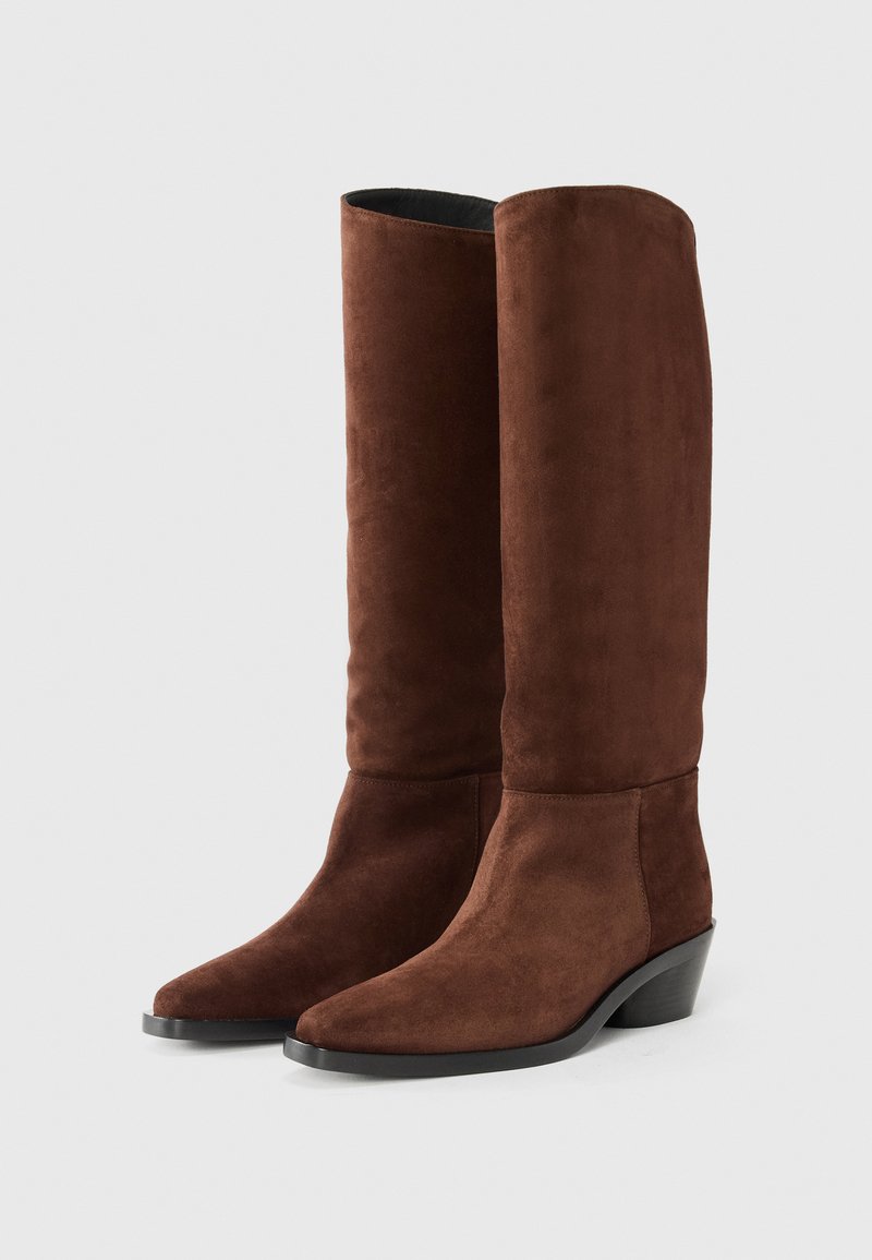 Brown suede knee-high boots with a pointed toe and a low stacked heel, featuring a smooth texture and minimalistic design.