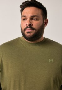 Olivenfarbiges T-Shirt aus weichem Stoff, mit Rundhalsausschnitt und einem kleinen Logo in einem helleren Grün auf der Brust.
