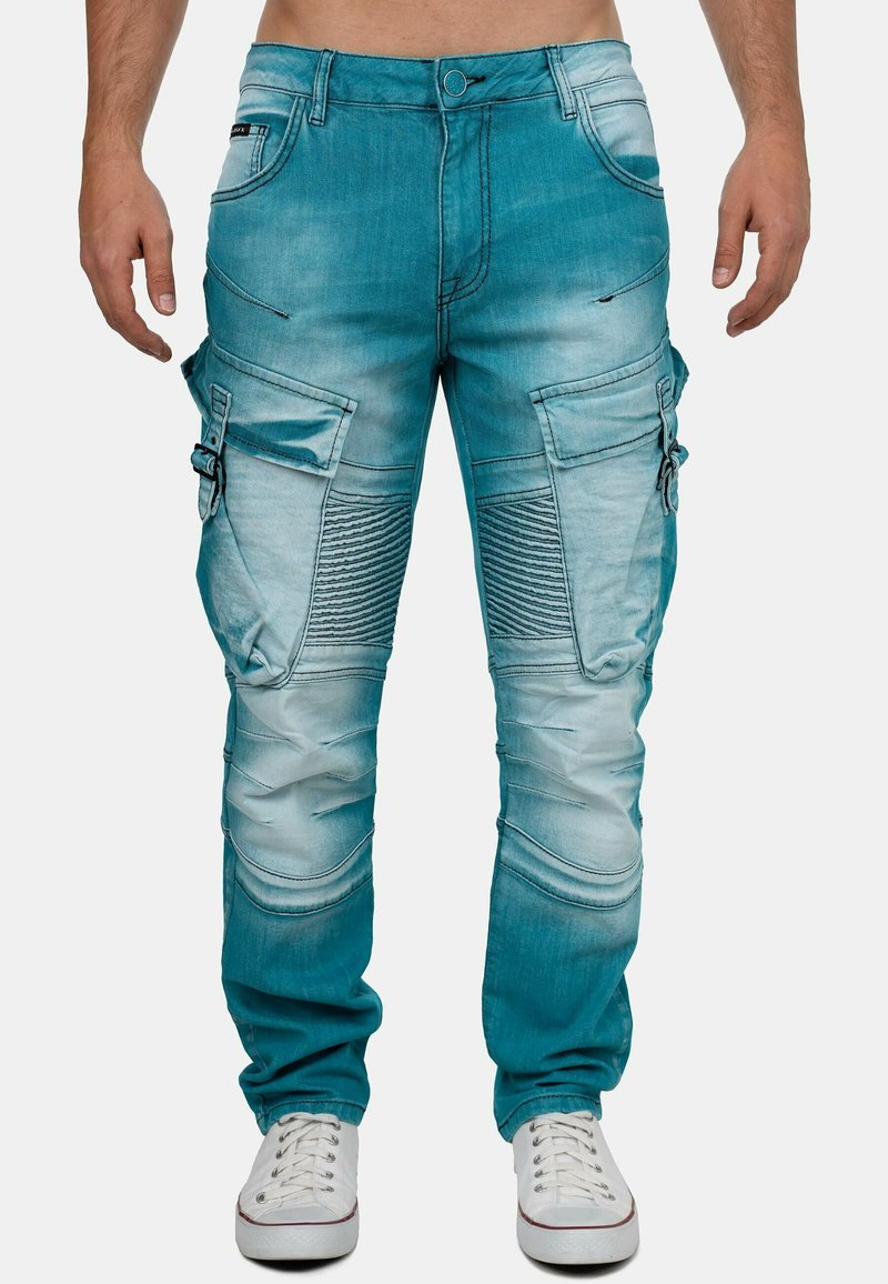Pantalons cargo en denim turquoise avec des détails côtelés, plusieurs poches et une coupe décontractée. Présente des dégradés de couleur et des accents de couture.