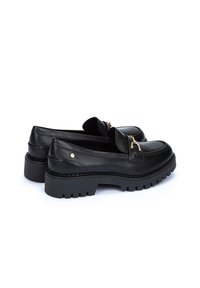 Mocasines de cuero negro con una suela gruesa, acentos de hardware dorado y una textura lisa. Diseñados con líneas clásicas y una base robusta.