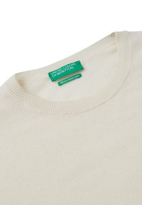 Suéter color crema hecho de lana merino. Presenta un cuello redondo y puños acanalados. La etiqueta indica "United Colors of Benetton".