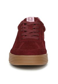 Sneaker in suede bordeaux con punta arrotondata, superficie testurizzata, lacci piatti e suola in gomma color tan con righe orizzontali. Logo visibile sulla linguetta.
