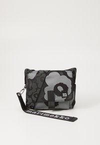 Black and gray floral print bag with adjustable strap. Made of durable fabric, features a front flap and logo detail. Compact and structured design.