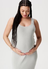 Lichtgrijze geribde jurk met tankbandjes, aansluitende silhouet, zachte textuur en een ronde halslijn, gedragen door een persoon met gevlochten haar.