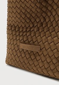 Καφέ υφαντή τσάντα χειρός από υλικό με υφή, σε ορθογώνιο σχήμα. Διαθέτει μικρή ανάγλυφη ετικέτα λογότυπου με την επιγραφή "NAGHEDI."