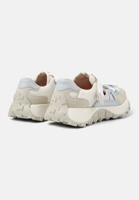 Zapatillas beige y azul claro hechas de malla y gamuza. Suela blanca gruesa texturizada con patrones en zigzag. Cordones y acentos en el talón en colores a juego.