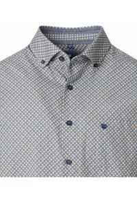 Kurzärmliges Hemd in Weiß mit einem kleinen geometrischen Muster in Blau und Braun. Mit Button-down-Kragen und Brusttasche.