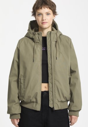 Olijfgroen bomberjack met capuchon, vooraan met rits, geribbelde manchetten en zoom; gedragen over een zwart crop-top. Vlotte textuur, casual ontwerp.