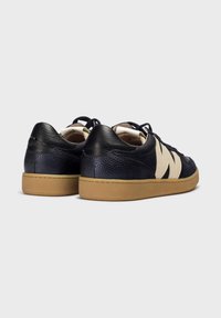 Zapatillas de cuero navy con acentos crema, punta redonda, superficie texturizada y suela de goma; cuenta con un logo lateral en contraste y cierre con cordones.