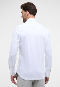 Witte lange mouwen overhemd met een rechte rug, knoopmanchetten en een klassieke kraag. Gemaakt van een gladde stof, met een getailleerde pasvorm.