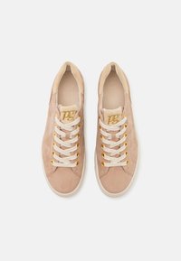 Hellrosa Wildleder-Sneaker mit cremefarbenen Schnürsenkeln, goldenen Ösen und einem weichen Innenfutter, das ein dezentes Logo auf der Zunge geprägt hat.