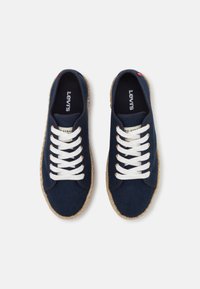 Námořnické plátěné tenisky s bílými tkaničkami, kulatou špičkou a přírodní juteovou podrážkou. Obsahují vyšívané logo značky na jazyku.