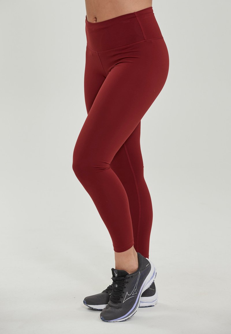 Bordeaux leggings met een hoge tailleband, rekbare stof, getailleerde pasvorm, een gladde textuur en zonder zichtbare patronen of accenten.