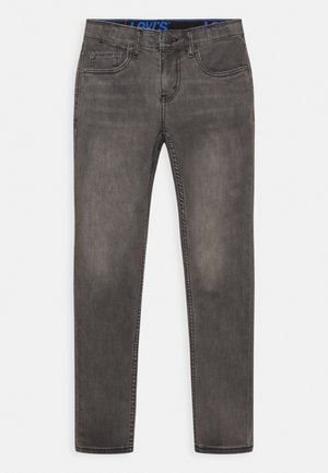 Jean en denim gris foncé avec une coupe slim, présentant un design classique à cinq poches et un logo bleu Levi’s sur la ceinture.