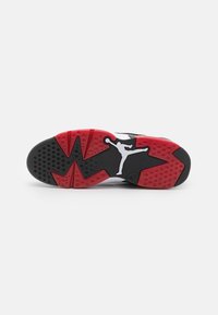 Semelle d'une chaussure de sport noire, rouge et blanche avec un logo Jumpman au centre et des motifs texturés antidérapants sur la partie inférieure.