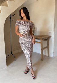 Rochie cu umerii la vedere, în imprimeu zebra bej și alb, siluetă ajustată, detalii pliate, asortată cu sandale negre cu curele.